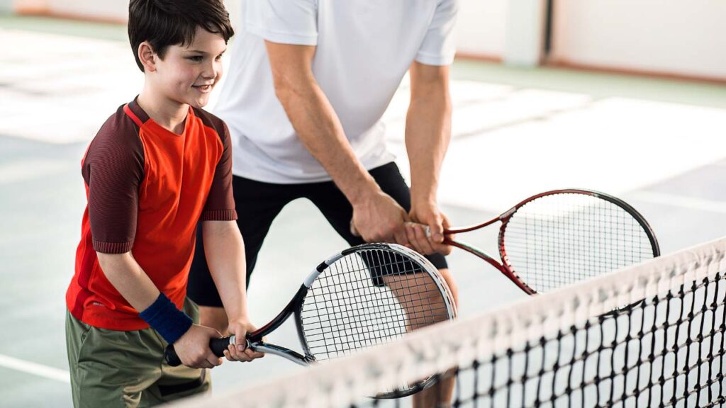 young boy with adult testing tennis racket
