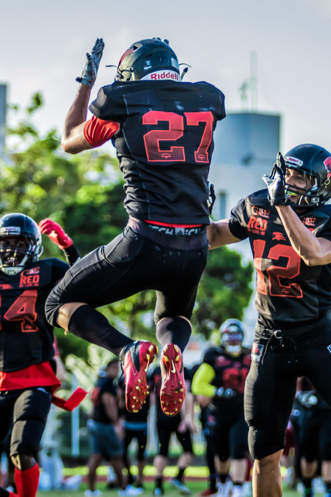 Football player jumping in air and celebrating with teamates